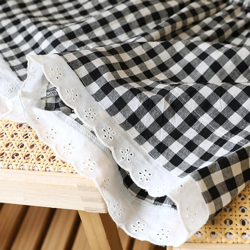 Gros plan sur la gaze de coton vichy noire et la bordure en dentelle blanche travaillée du short de nuit.