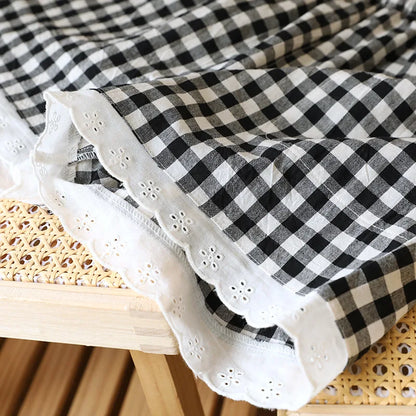Gros plan sur la gaze de coton vichy noire et la bordure en dentelle blanche travaillée du short de nuit.