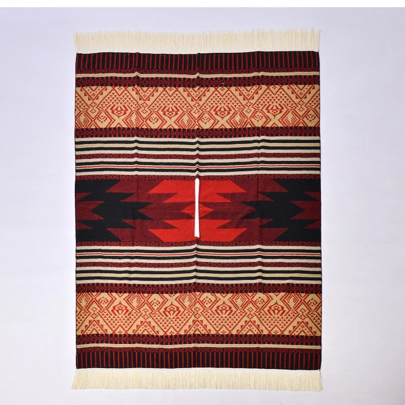 Poncho rouge et noir à plat avec motifs tribaux denses et bordures frangées blanches.
