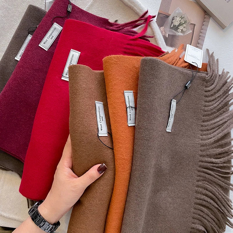 Détail de la texture douce et des franges d'une écharpe en laine coloris marron tenue à la main