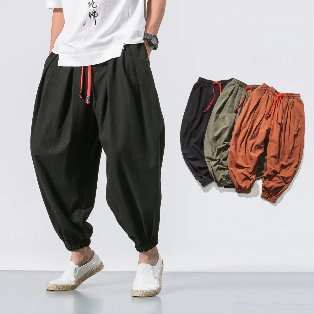 Pantalon sarouel homme noir en lin et coton porté avec des chaussures blanches, vue de face.