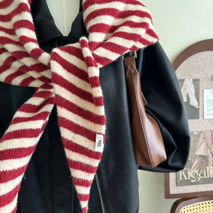 Détail de la maille tricotée et du motif rayé d'une écharpe triangle hivernale rouge et crème