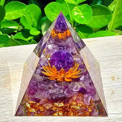 Main présentant une pyramide d'orgonite, soulignant la transparence et la qualité de la fabrication artisanale.