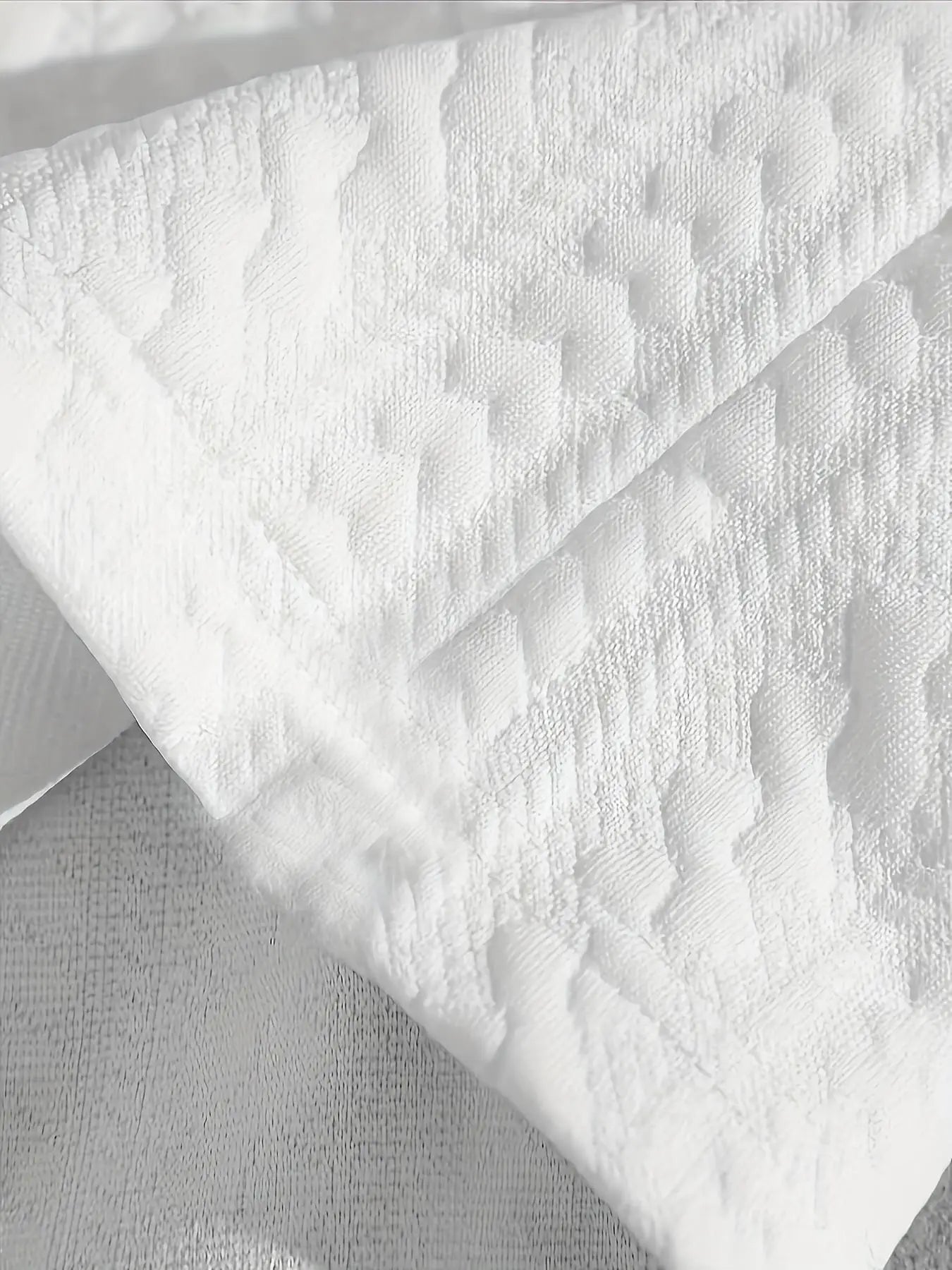 Gros plan sur le tissu jacquard blanc au motif gaufré en relief, soulignant la texture douce et respirante.