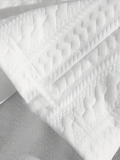 Gros plan sur le tissu jacquard blanc au motif gaufré en relief, soulignant la texture douce et respirante.
