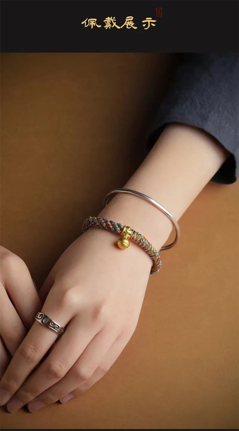Processus de fabrication manuelle d'un bracelet tibétain avec du fil doré et rouge.