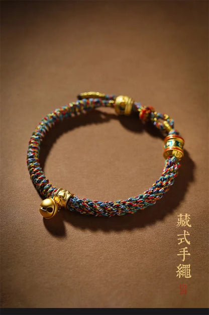 Mains d'artisan tressant avec précision la corde rouge du bracelet porte-bonheur.