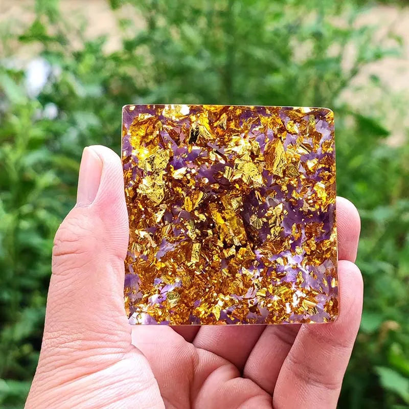 Vue de dessous : base carrée d'une pyramide d'orgonite avec éclats de feuilles d'or et améthyste.