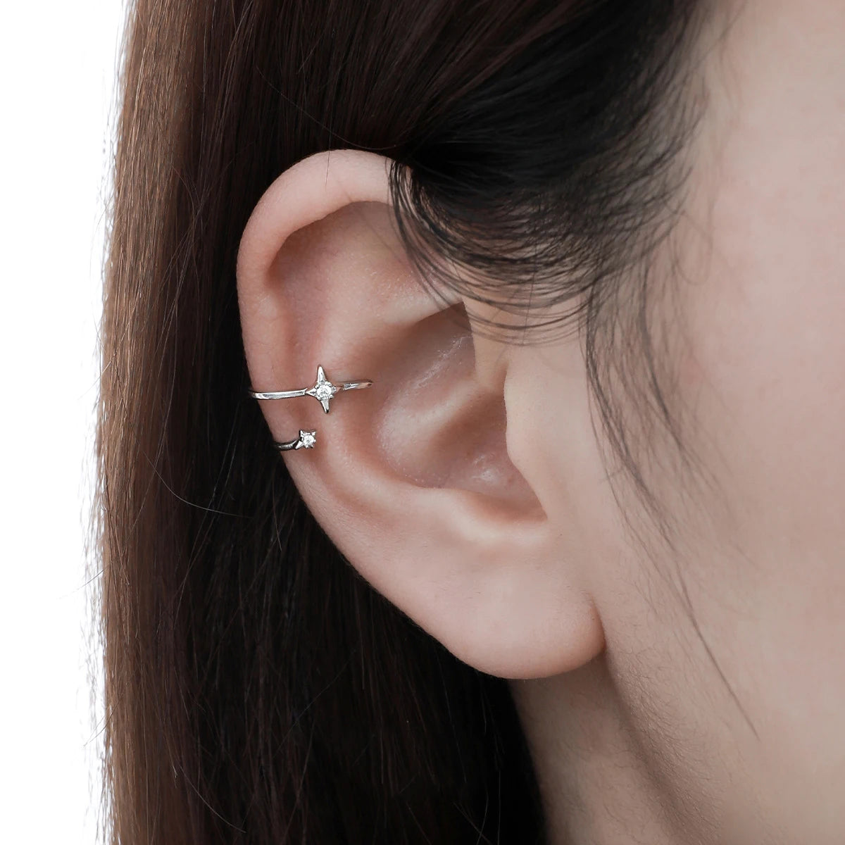Bague d'oreille étoile en argent portée sur le cartilage d'une femme, ornée de zircons scintillants.