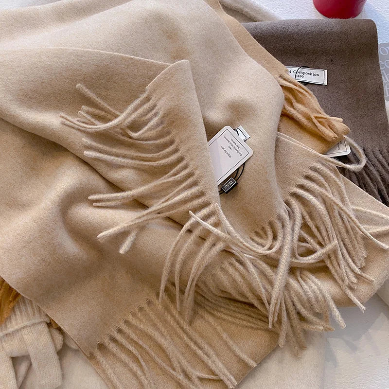 Zoom sur les franges et la maille douce d'une écharpe pashmina beige clair.