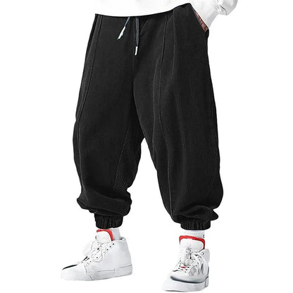 Pantalon large en velours côtelé noir, coupe zen avec cordon de serrage et chevilles resserrées.