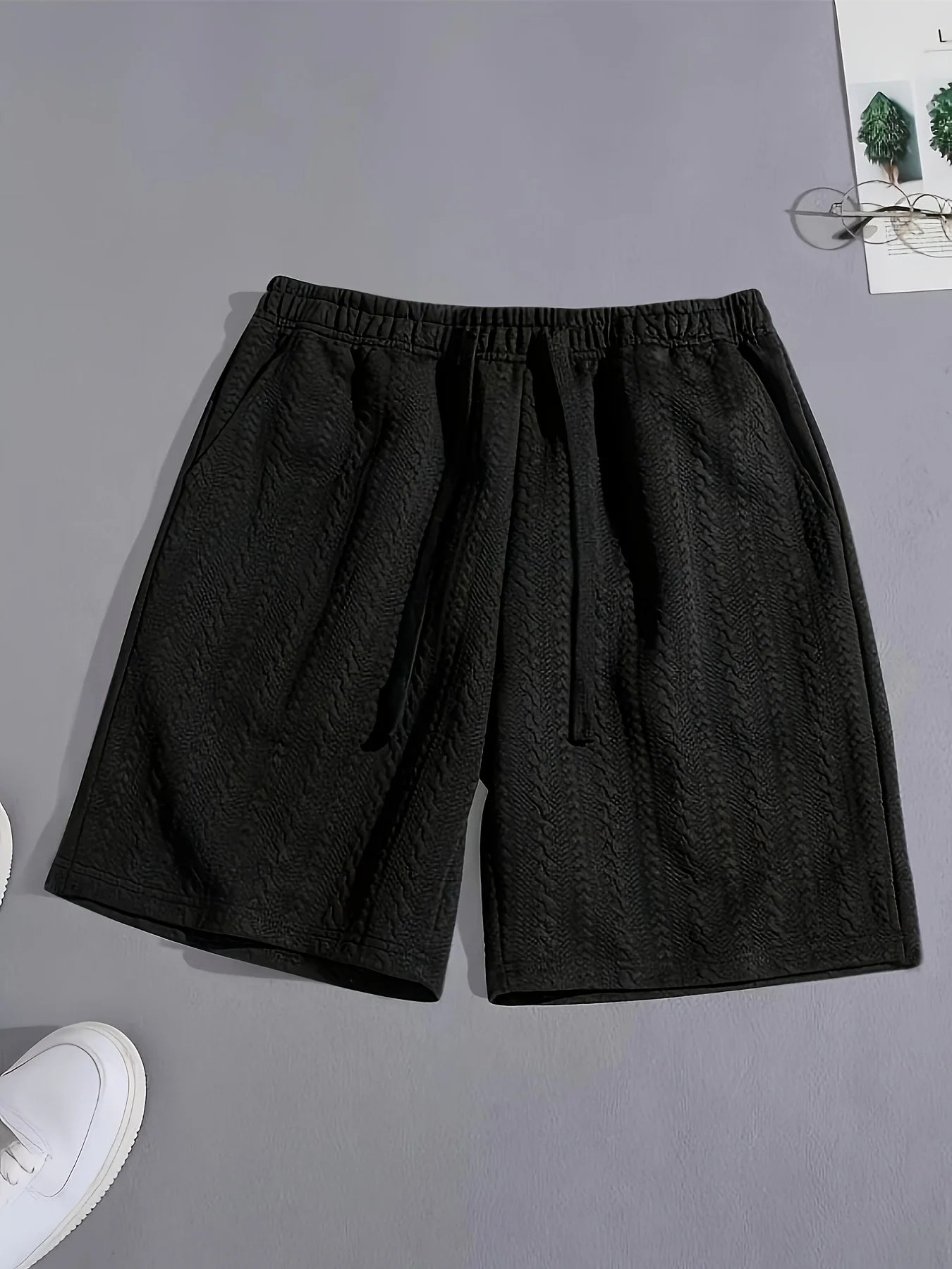 Vue à plat du short de détente noir en jacquard texturé, alliant style minimaliste et confort absolu.