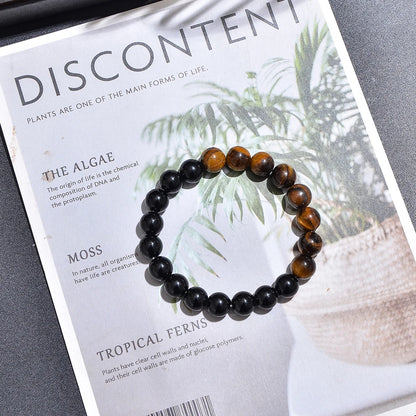 Bracelet élastique en pierres naturelles d'œil de tigre et onyx noir posé à plat.