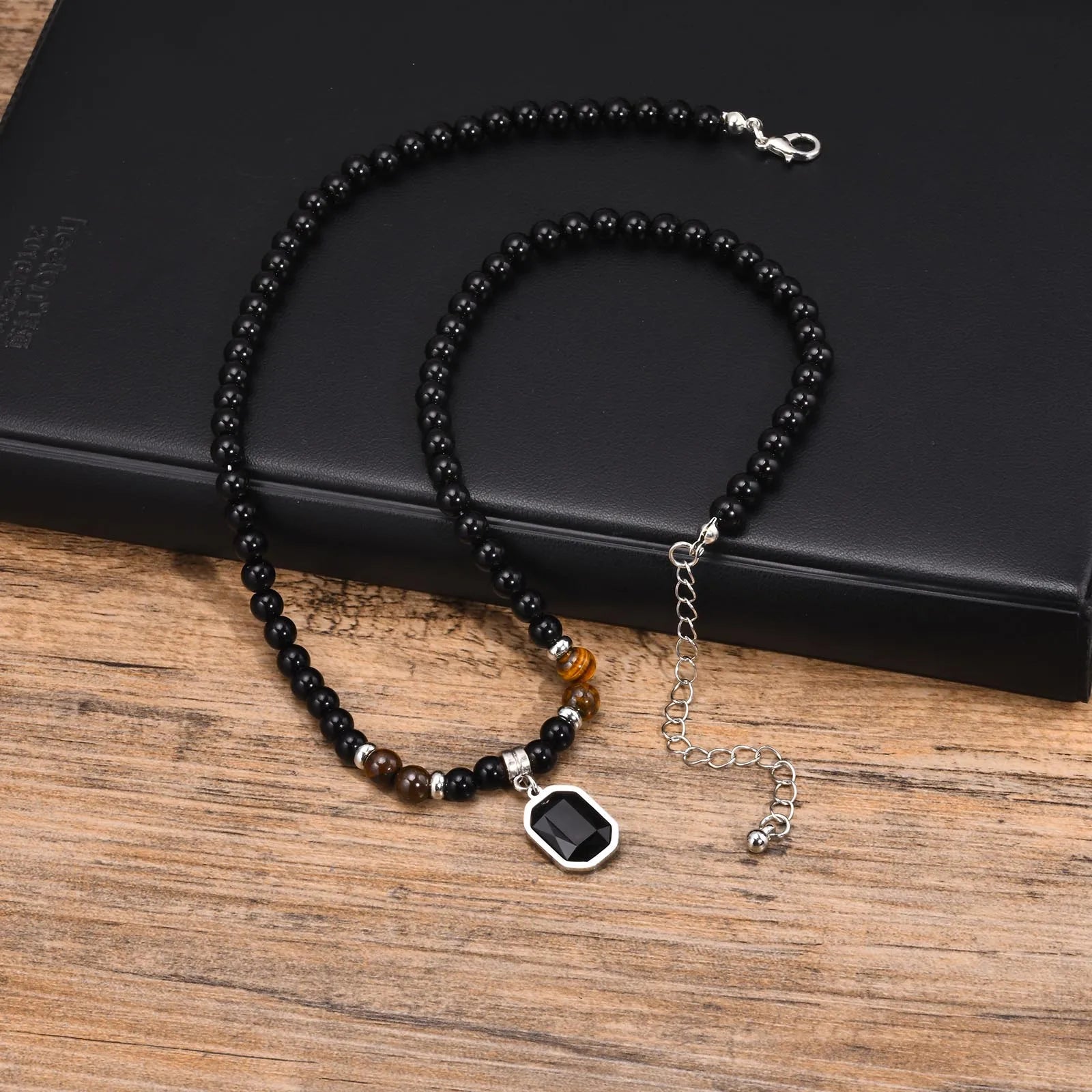Vue d'ensemble du collier zen pour homme montrant l'alternance des perles noires et des accents marron œil de tigre.