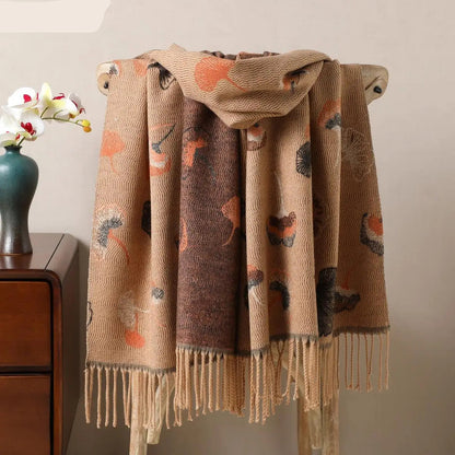 Écharpe pashmina beige et marron à motifs floraux drapée sur une chaise en bois.