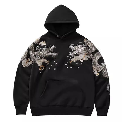Détail de la face avant du hoodie noir présentant des broderies de dragons symétriques sur le torse et les manches.