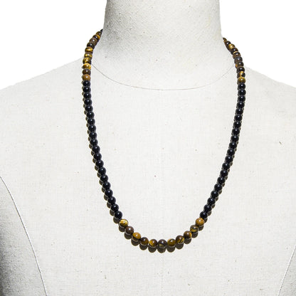 Collier de protection en onyx et œil de tigre présenté sur un buste de mannequin blanc.