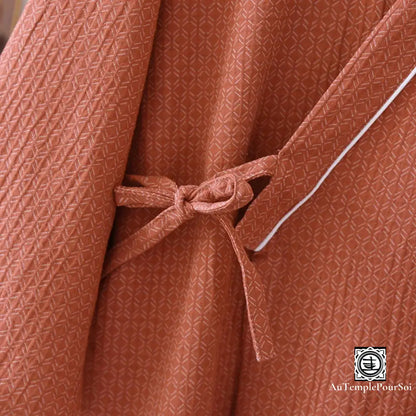 Gros plan sur le nœud de la ceinture du kimono terracotta, accentuant la texture du tissu et l'élégance du design.